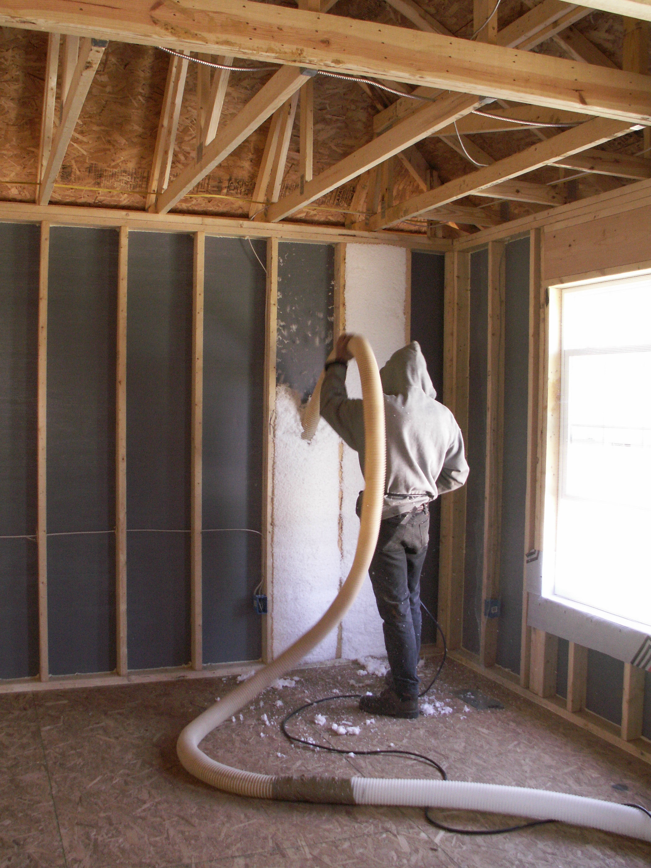 Blown fiberglass insulation fills netted wall cavities.