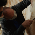 Right – an instructor shows a student how to cut batt insulation around wiring rather than compressing the batt behind the wiring. 